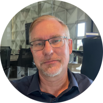 headshot of Steven B Garschke co-founder of relocate · brazil ENGLISH HOUSE in a dark blue shirt. In the background, office